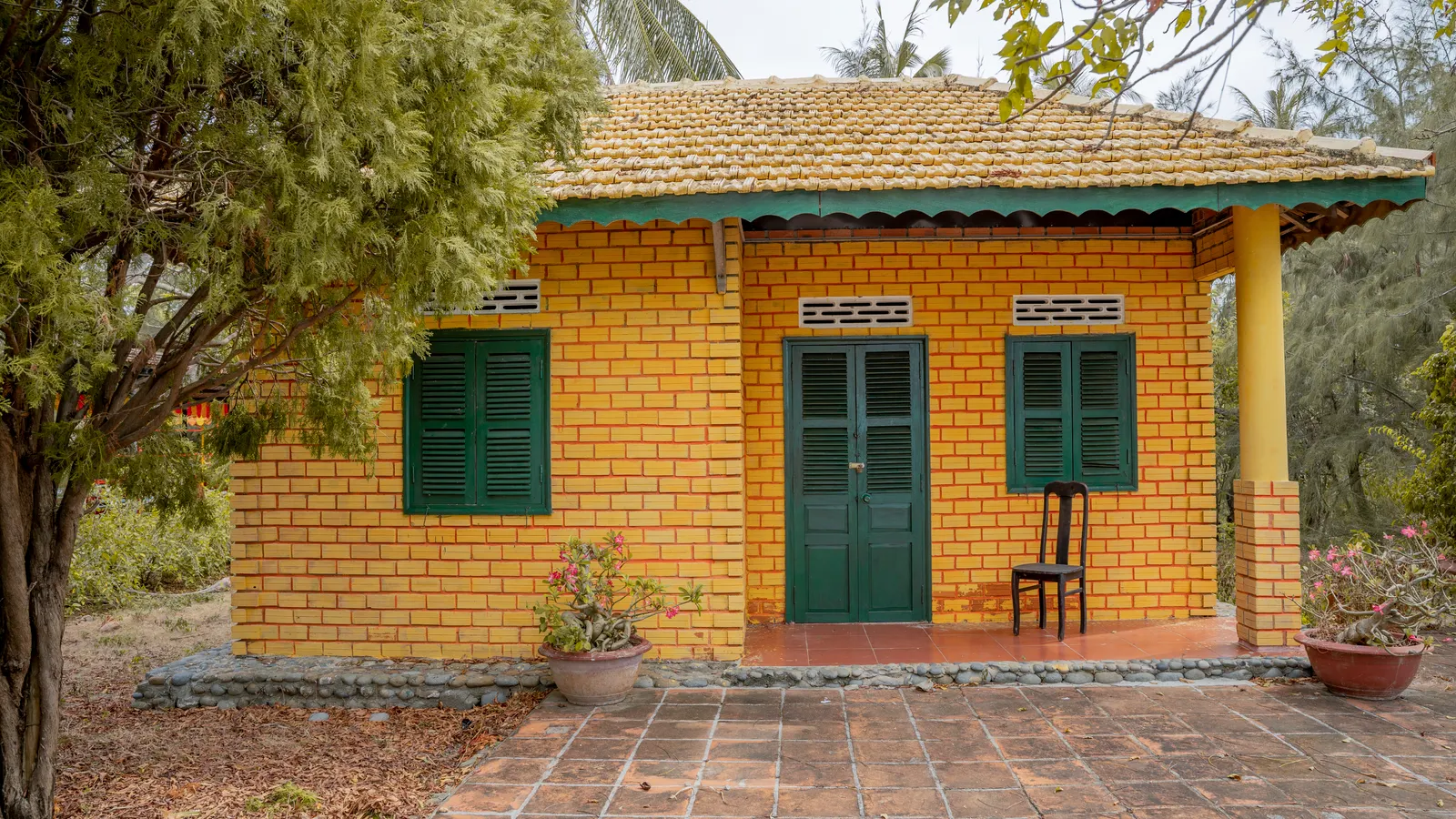 Foto ilustrasi rumah bata kuning di antara pepohonan