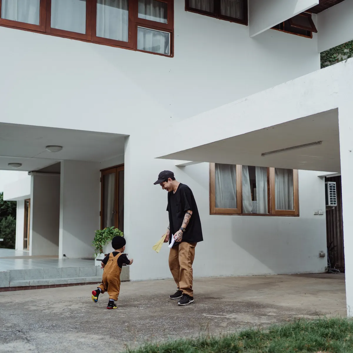 Ayah dan anak bermain di depan rumah bercat putih